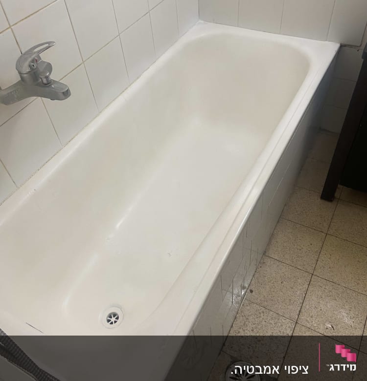 אמבטיה לבנה עם ברז מתכת על קיר אריחים